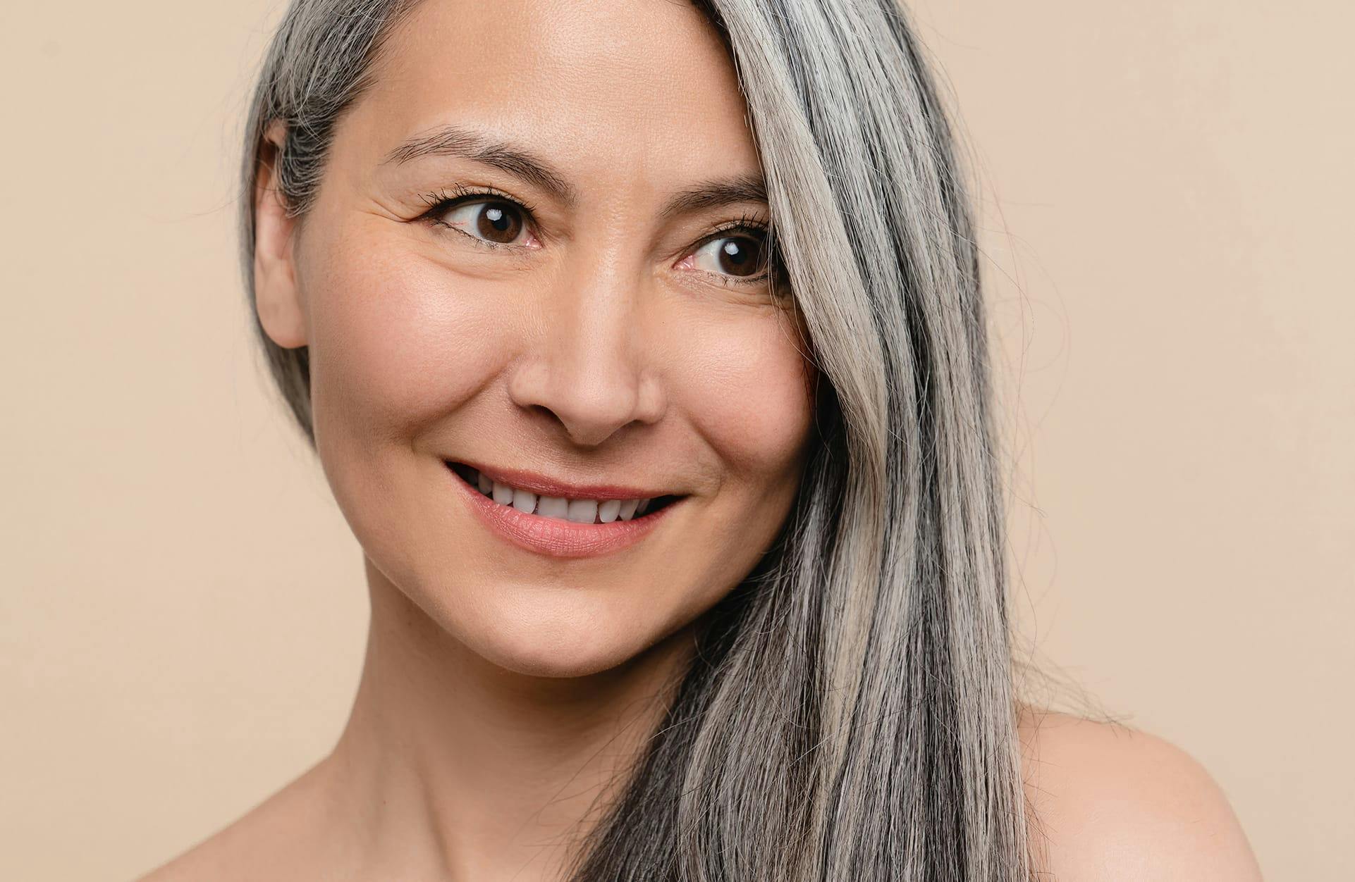 close up of older asian woman smiling and looking off camera