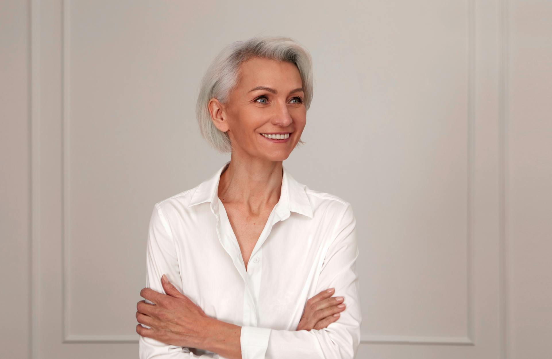 older woman with grey hair in a white button down shirt smiling