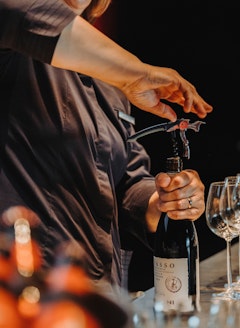 Event Catering Service öffnet Wein mit Korkenzieher