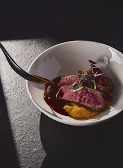 Chef drips gravy over Roast Beef with Polenta at KKL Lucerne