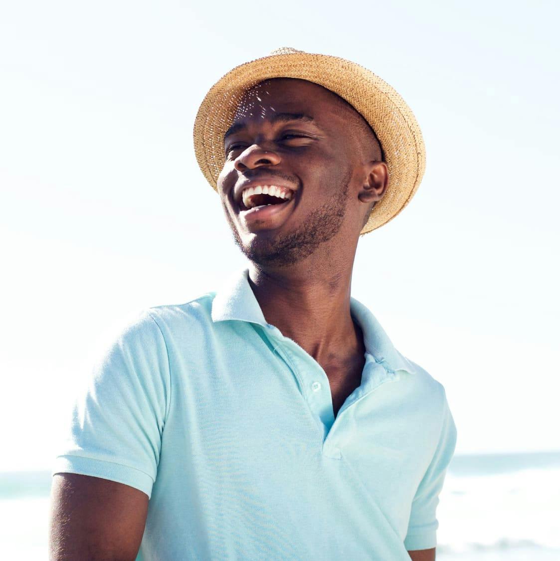 man smiling in hat with water behind him.