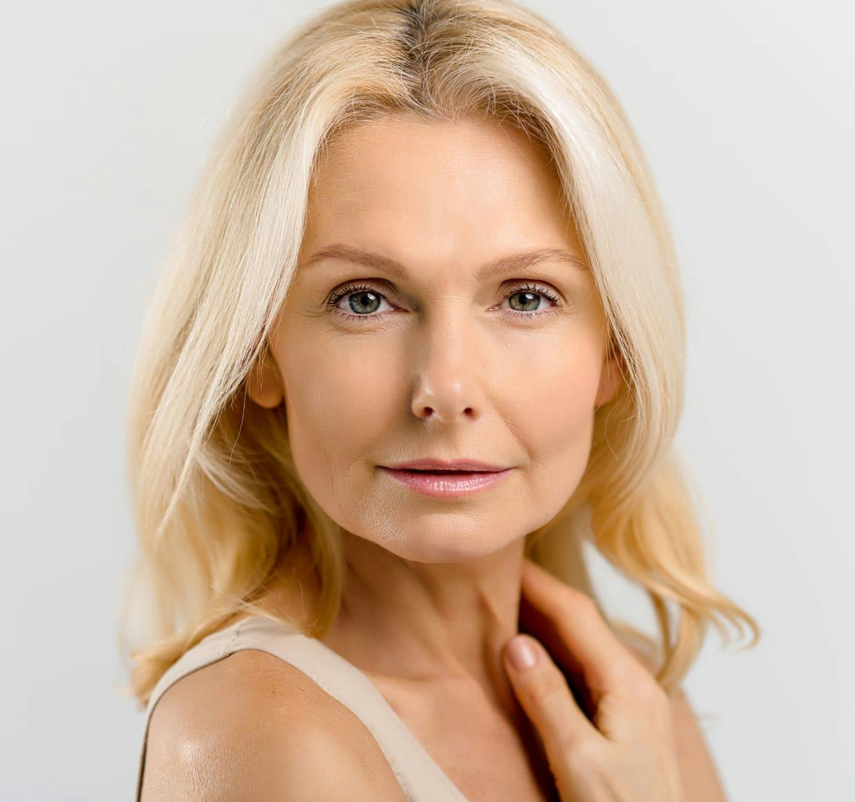 blond woman with blue eyes and a white top posing for a picture