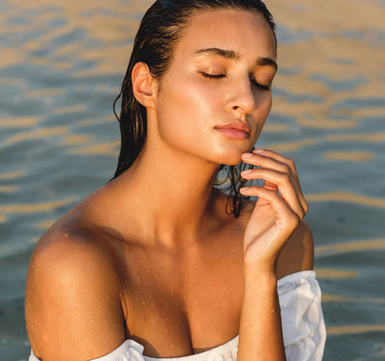 woman in white dress standing in water with eyes closed