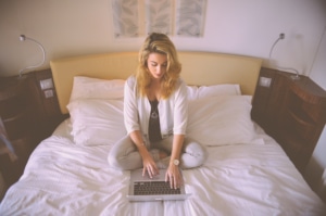 woman sitting on a bed with a laptop