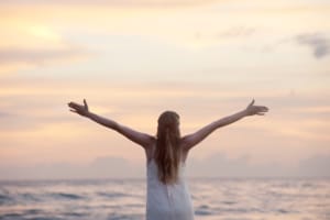 woman wiht her hands raised on a beach