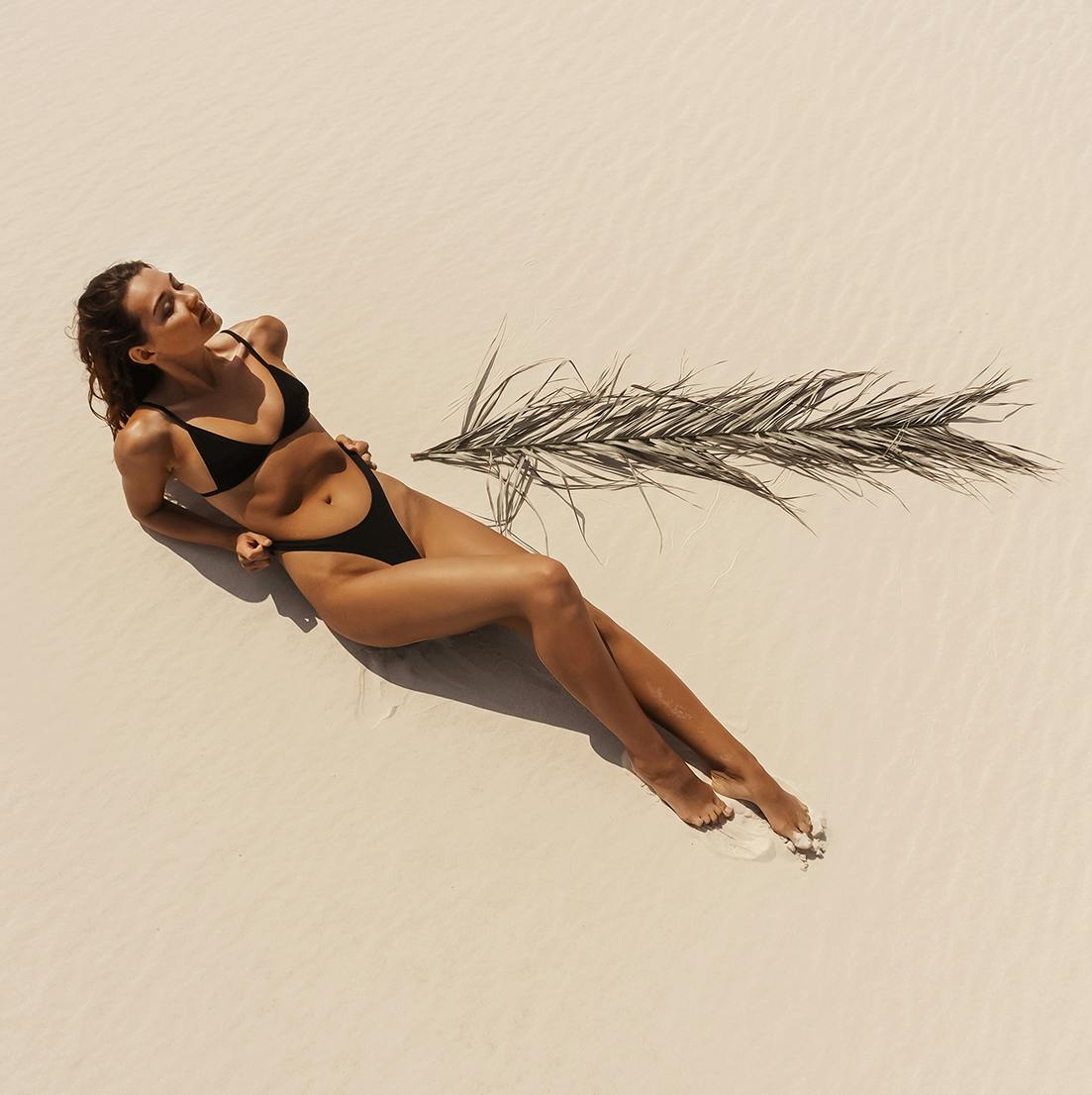 woman laying on the beach in black bikini