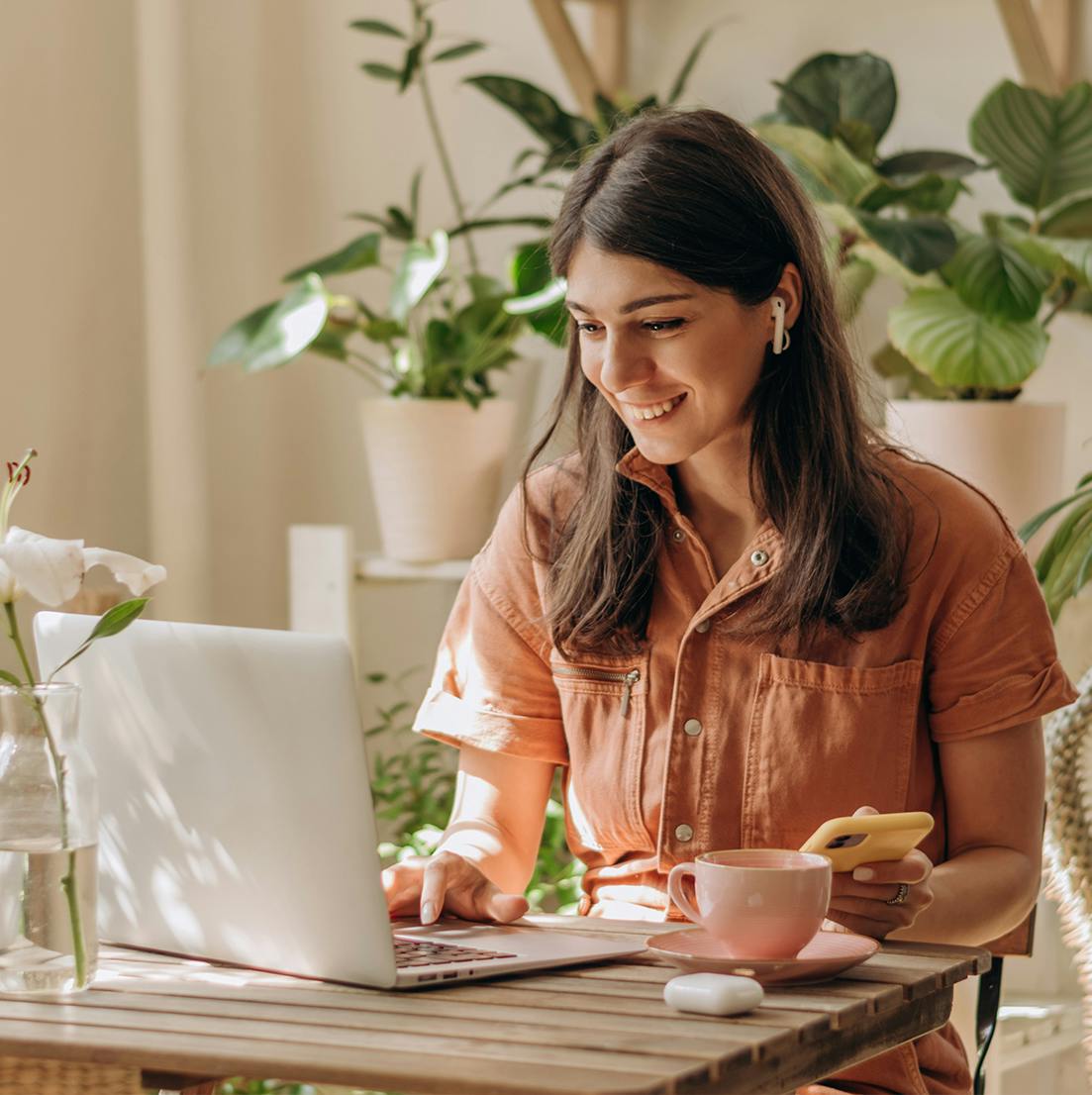 woman sitting at a table with a laptop and a cup of coffee