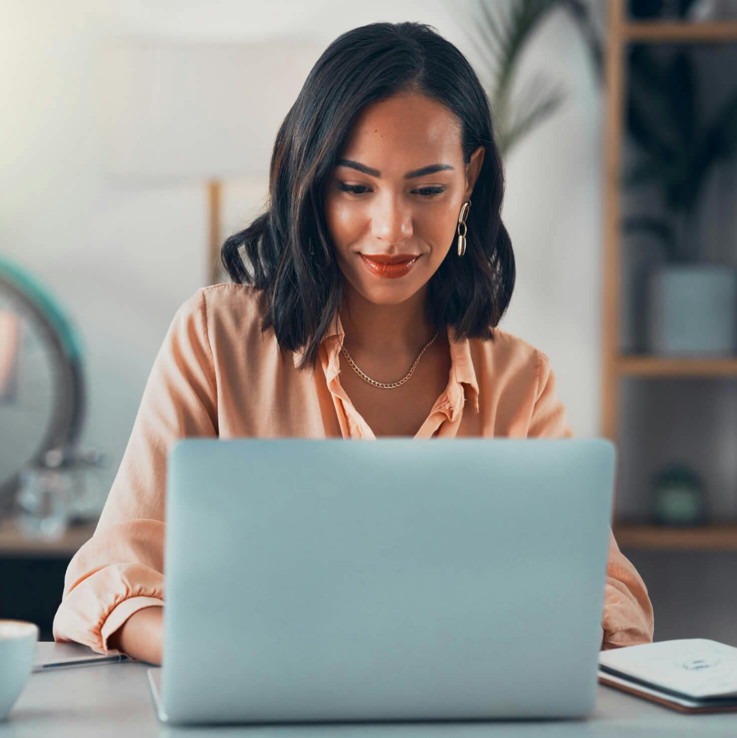 woman sitting at a table with a laptop and a cell phone