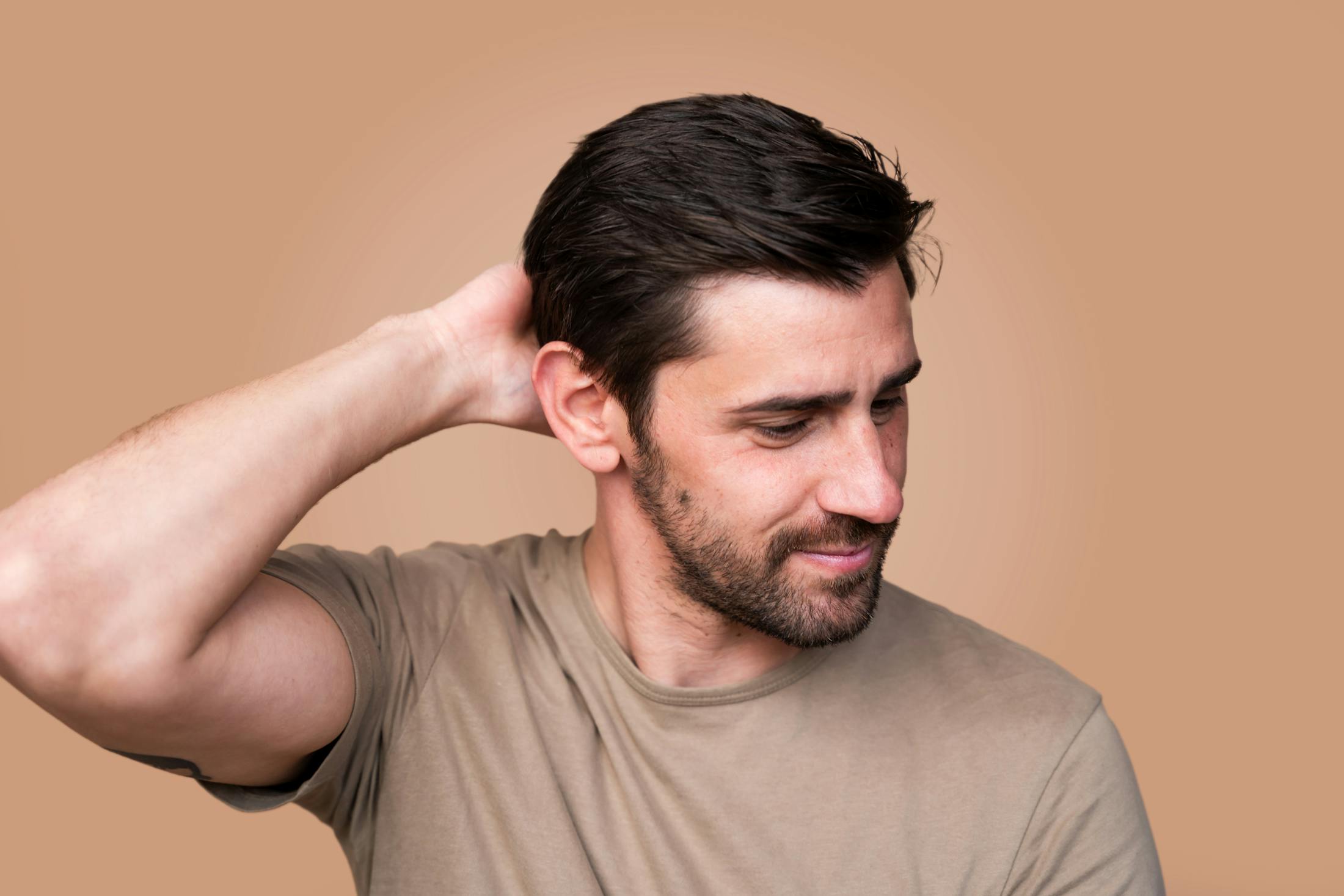 man with dark hair with hand on the back of his neck