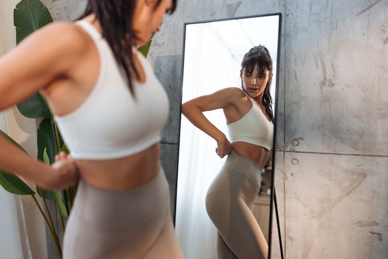 woman wearing tight leggings looking at the mirror