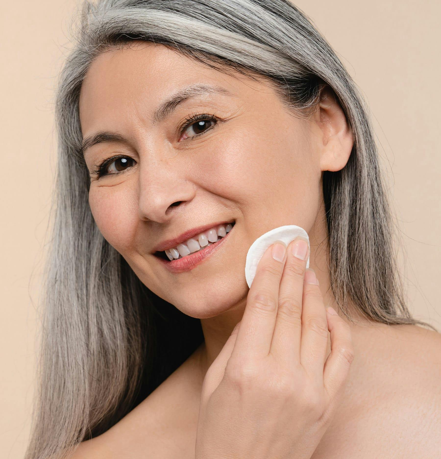 Woman with long grey hair wiping her face
