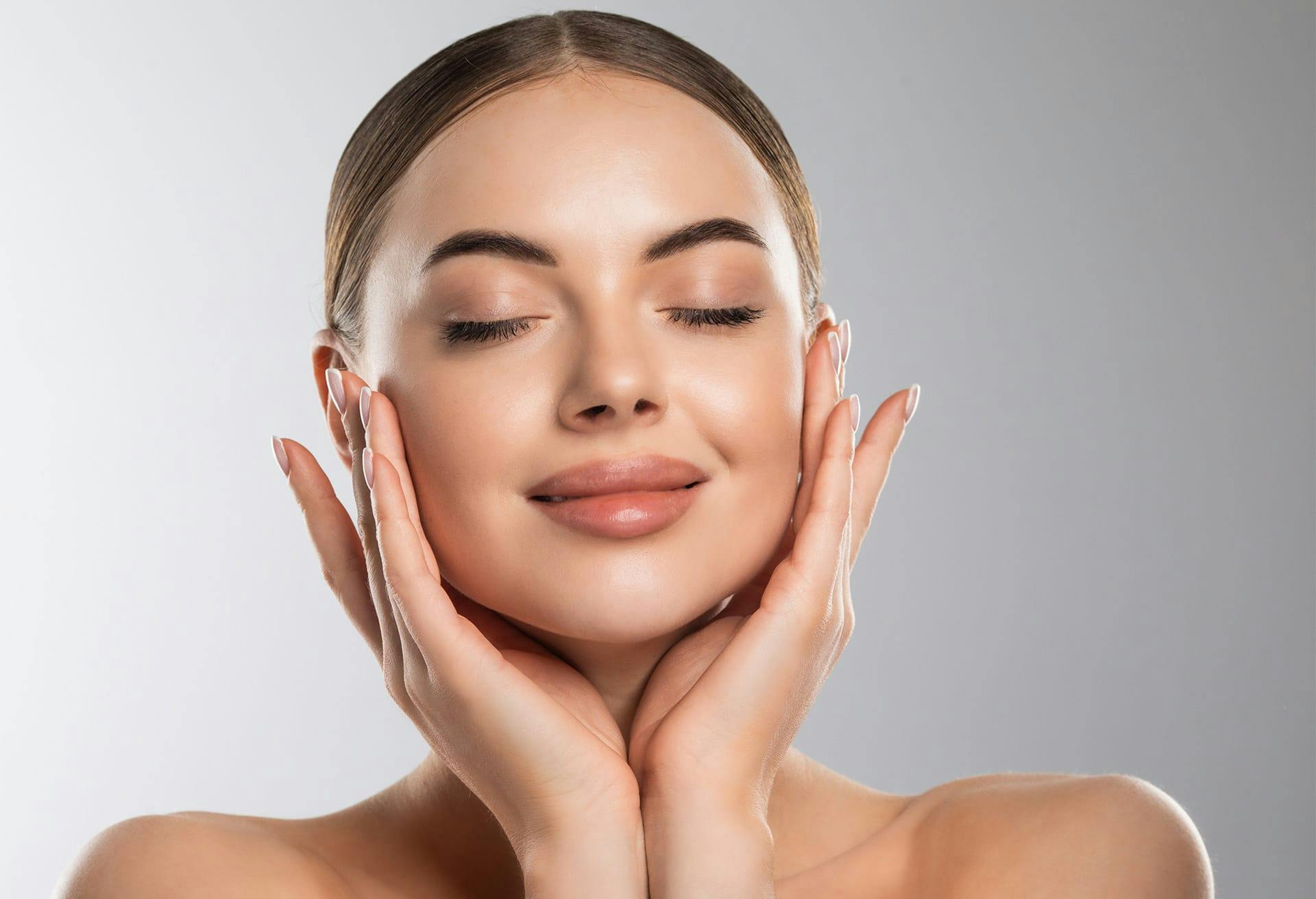 Woman smirking with her eyes closed with her hands on her face