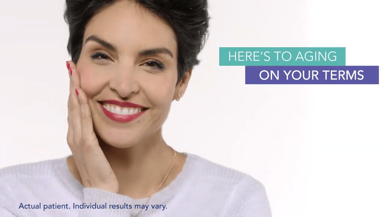 Restylane patient smiling, touching the side of her face