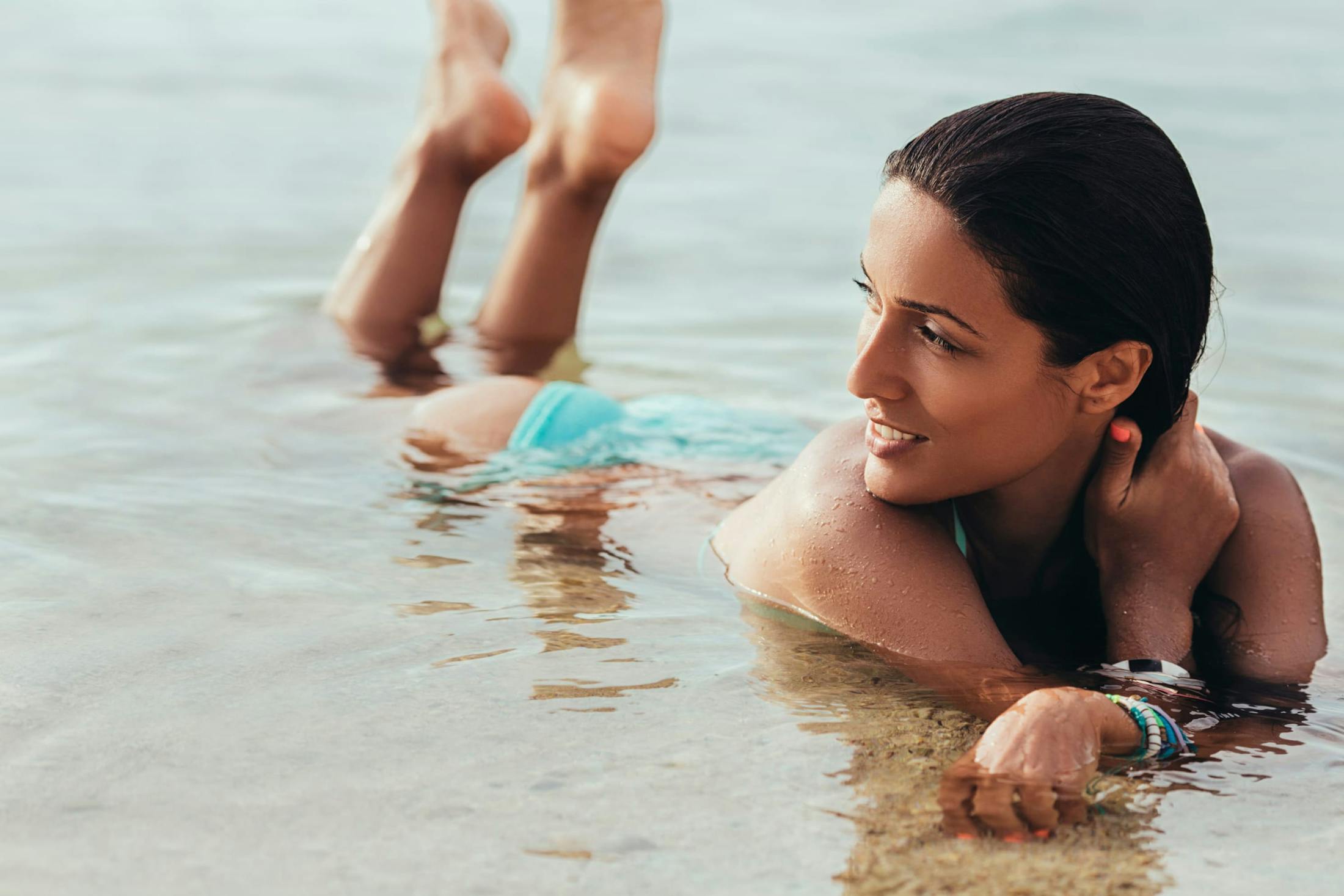 Woman laying on her stomach at the beach in the ocean