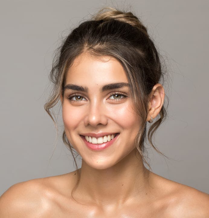Woman smiling with her hair pulled back with little curly strands framing her face