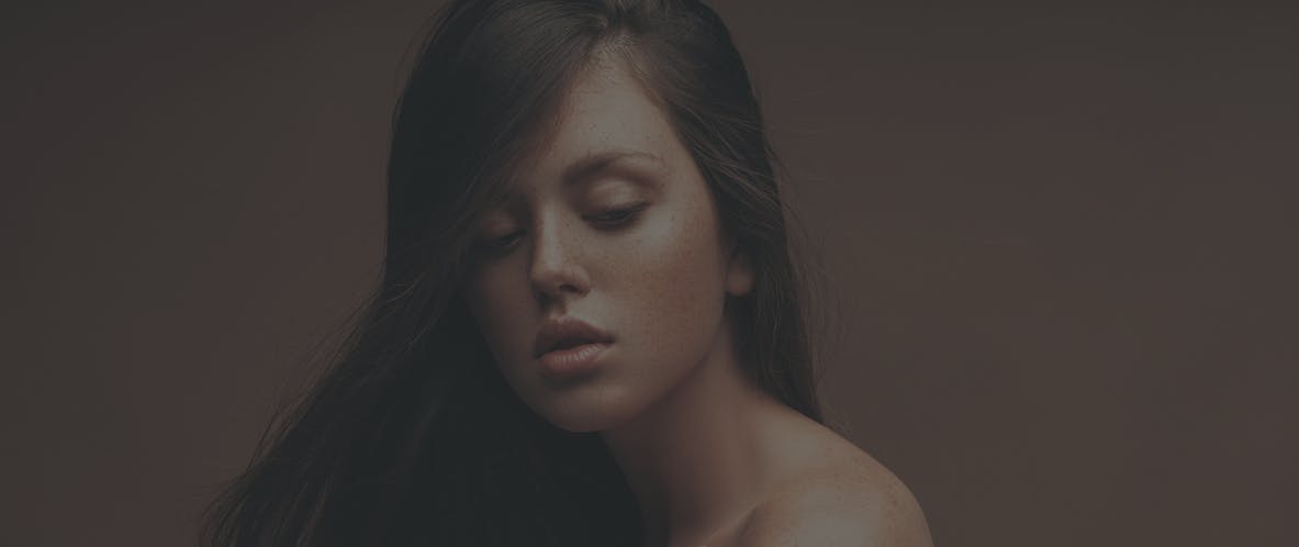 Studio shoot with  young woman with long dark hair and perfect skin. Her hands rest gently around her face. Her beatiful skin is to emulate the potential results of Toskani Skincare in Austin, TX with APSI