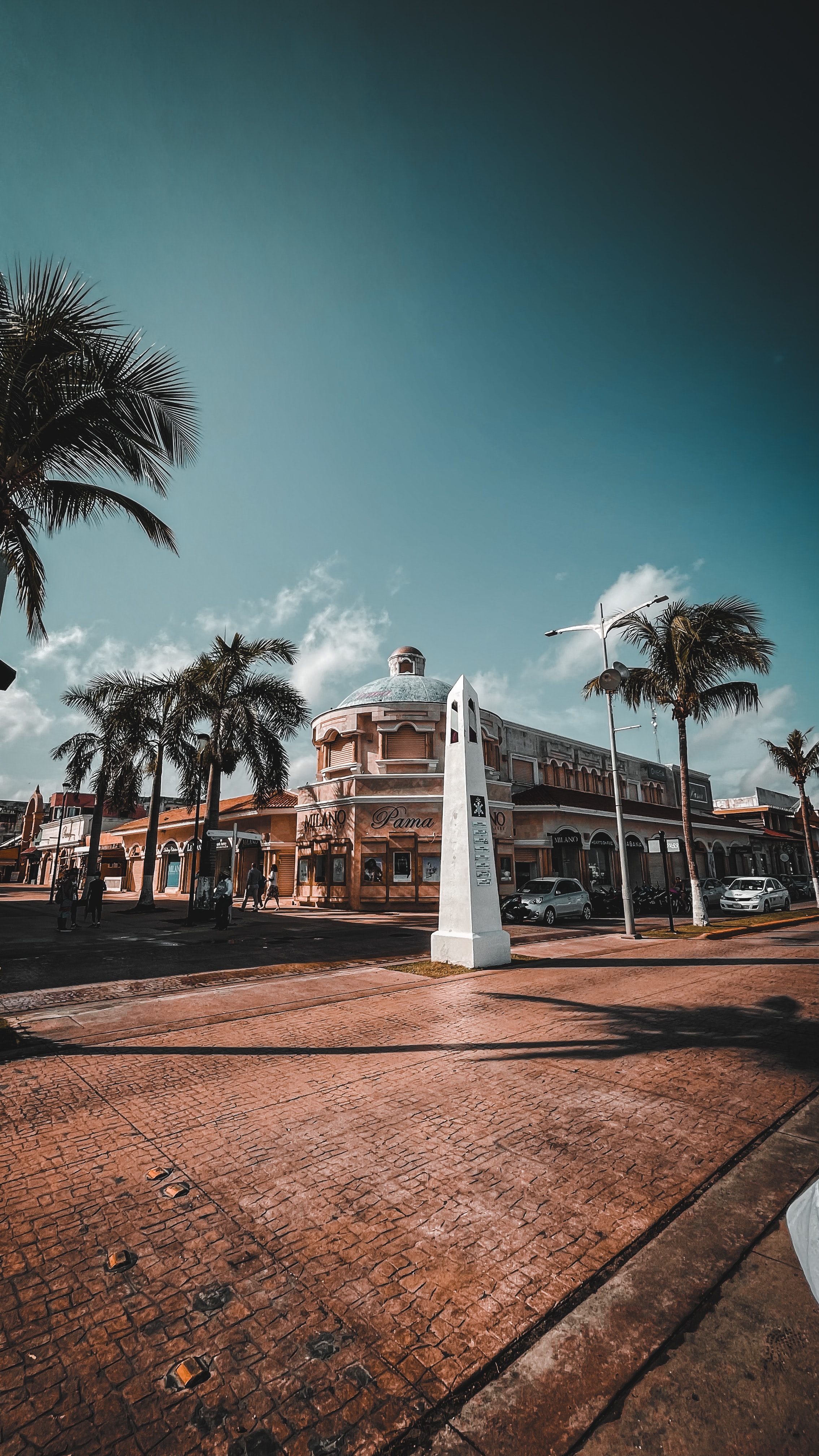 white and brown concrete building near palm trees under blue sky during daytime