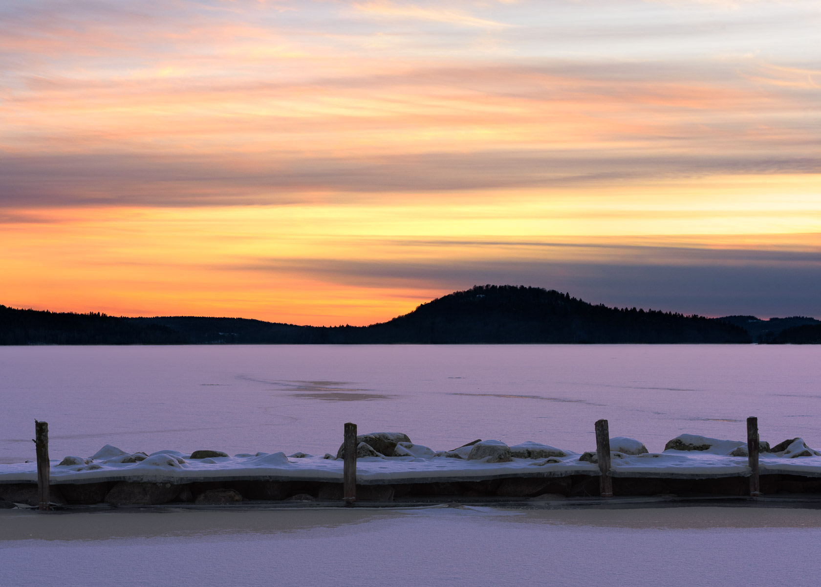 Solnedgången över ett snöklätt Öresjön och Hyltenäs kulle.