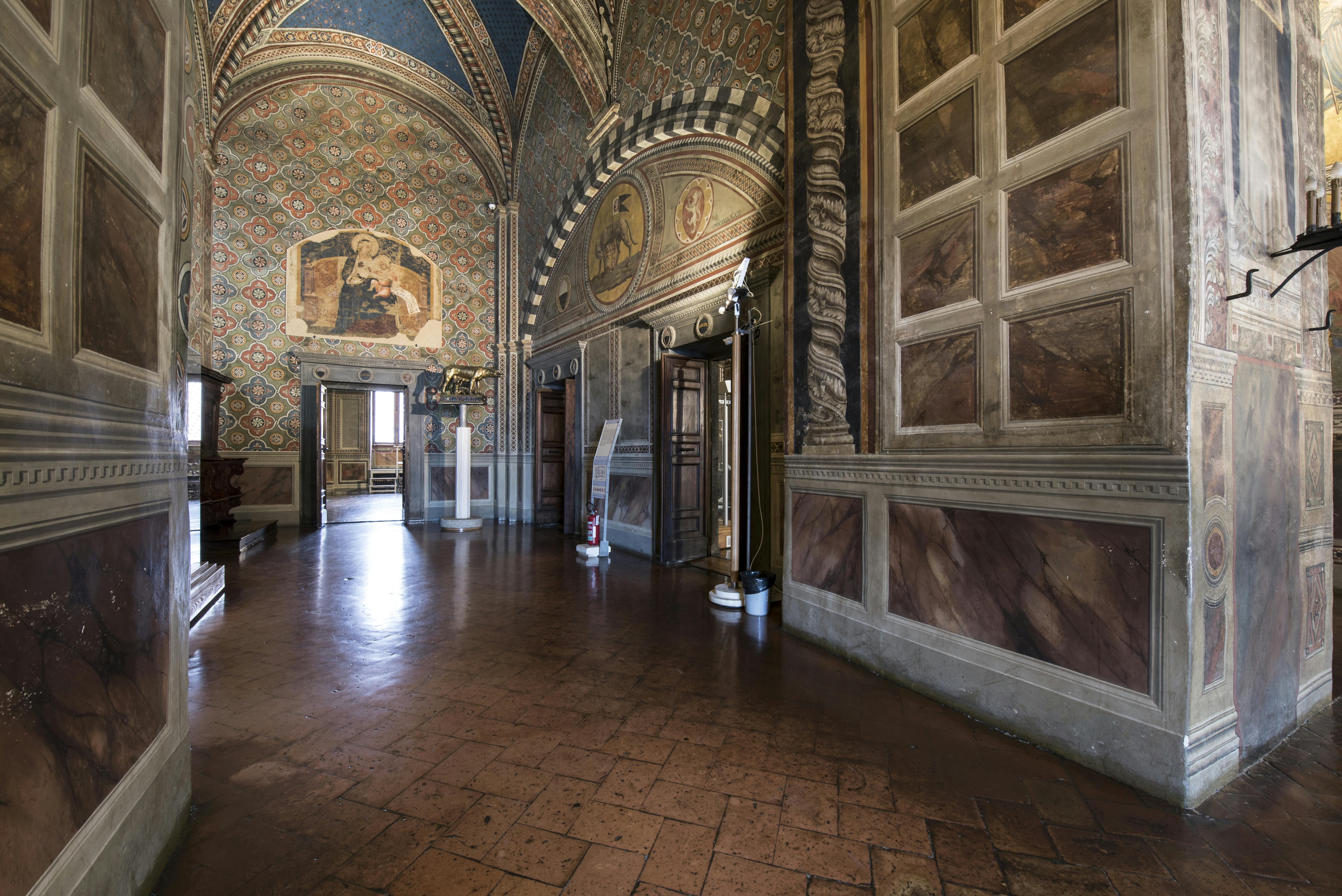 Foto del Vestibolo del Museo Civico di Siena, con vista sull'affresco staccato della Madonna col Bambino di Lorenzetti.