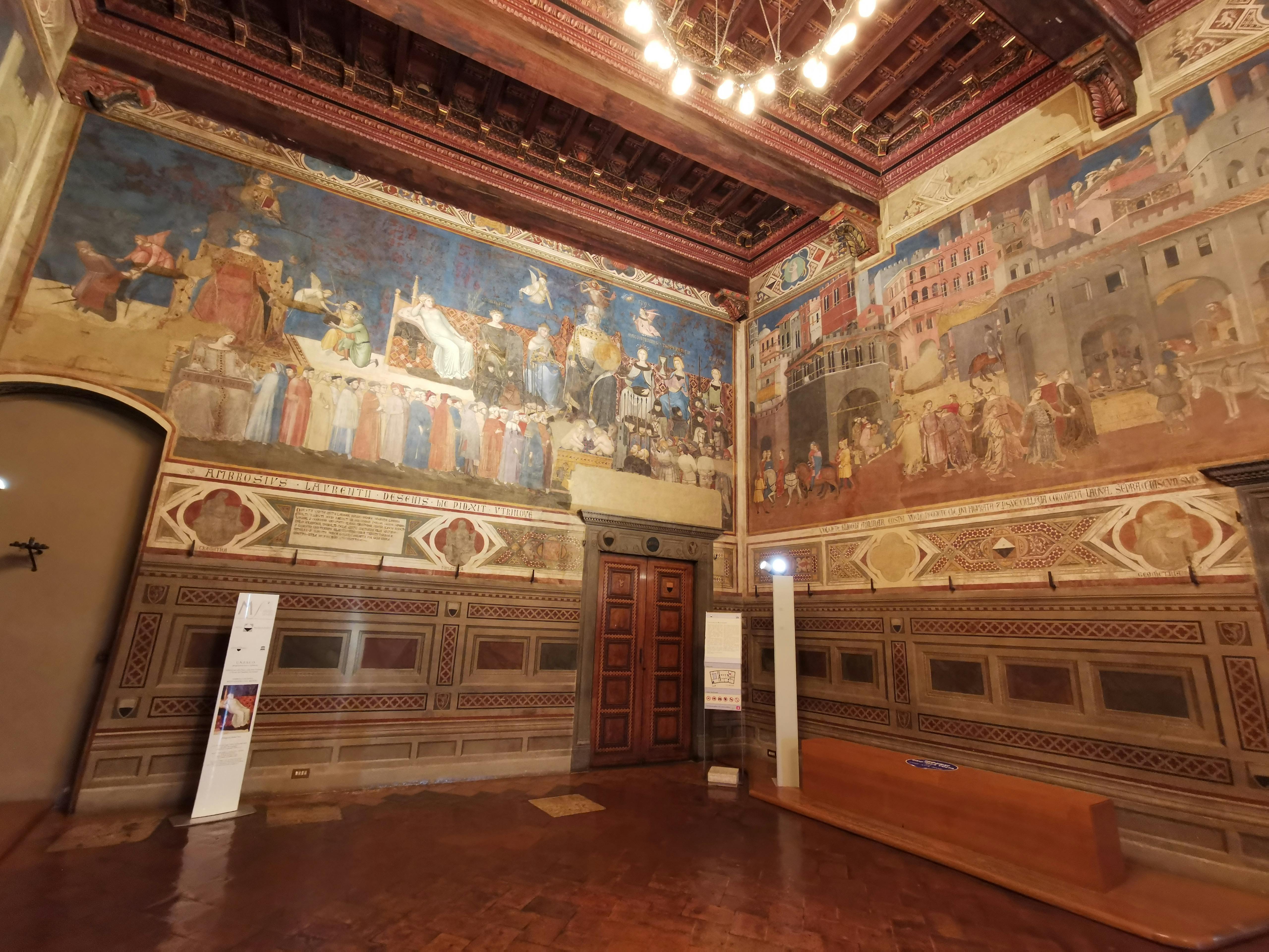 Foto della Sala della Pace del Museo Civico di Siena, con vista su parti del Ciclo del Buon Governo di Lorenzetti.