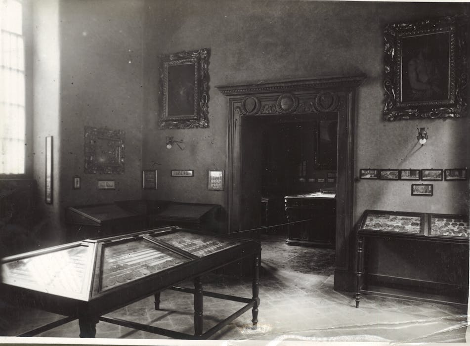 foto in bianco e nero di una sala antica con quadri ed espositori