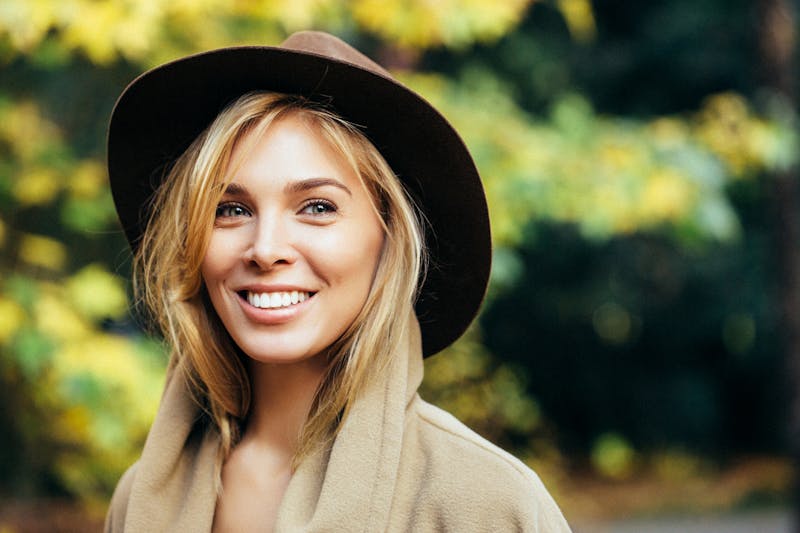 woman smiling outside wearing a hat