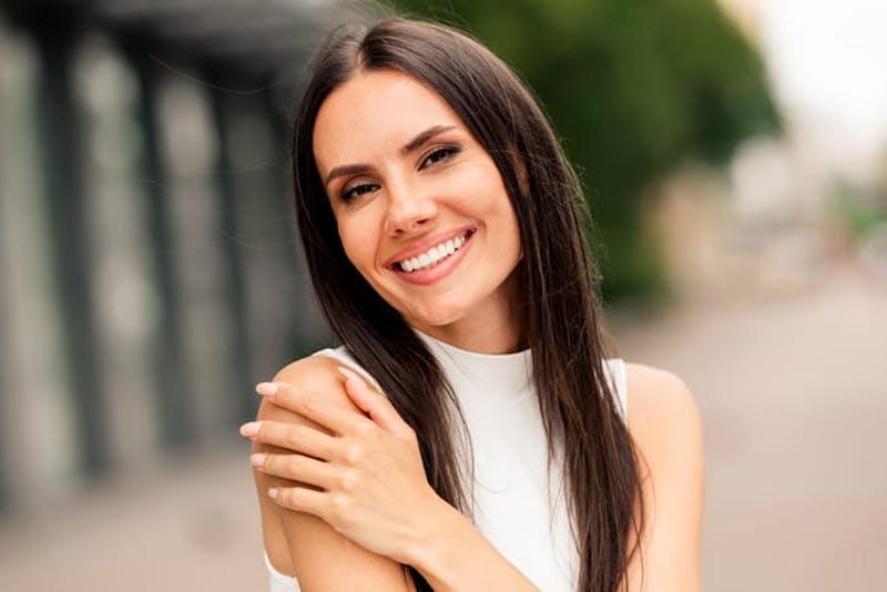 woman with her hand on her shoulder smiling