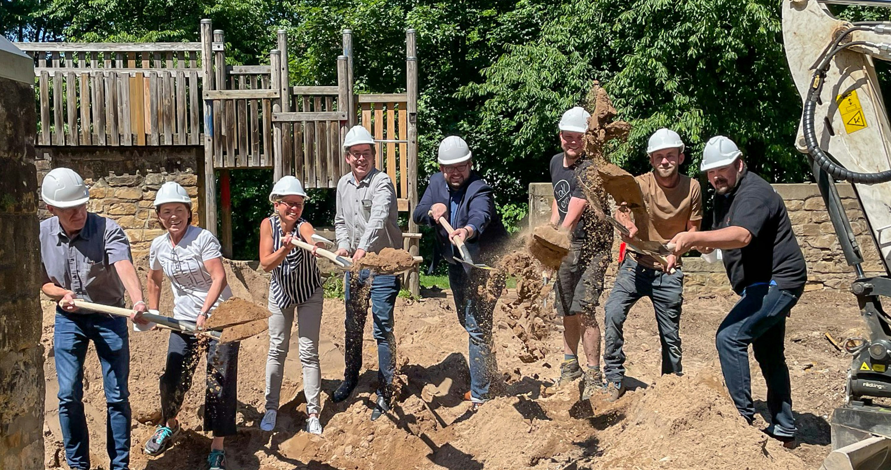 Team schaufelt auf einer Spieplatz Baustelle