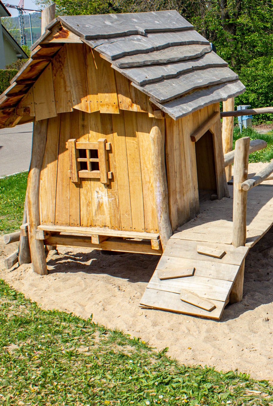 Ein Häuschen aus Holz mit Sandkasten und Kletterbalken