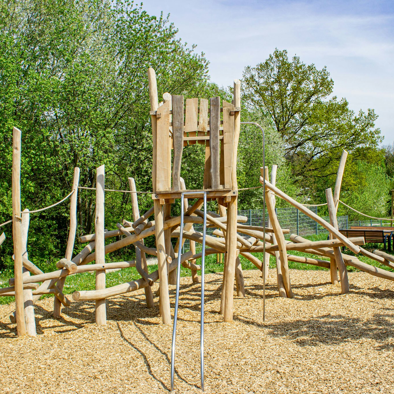 Ein Holzturm mit einer Rutsche, Kletterbalken und Seilen