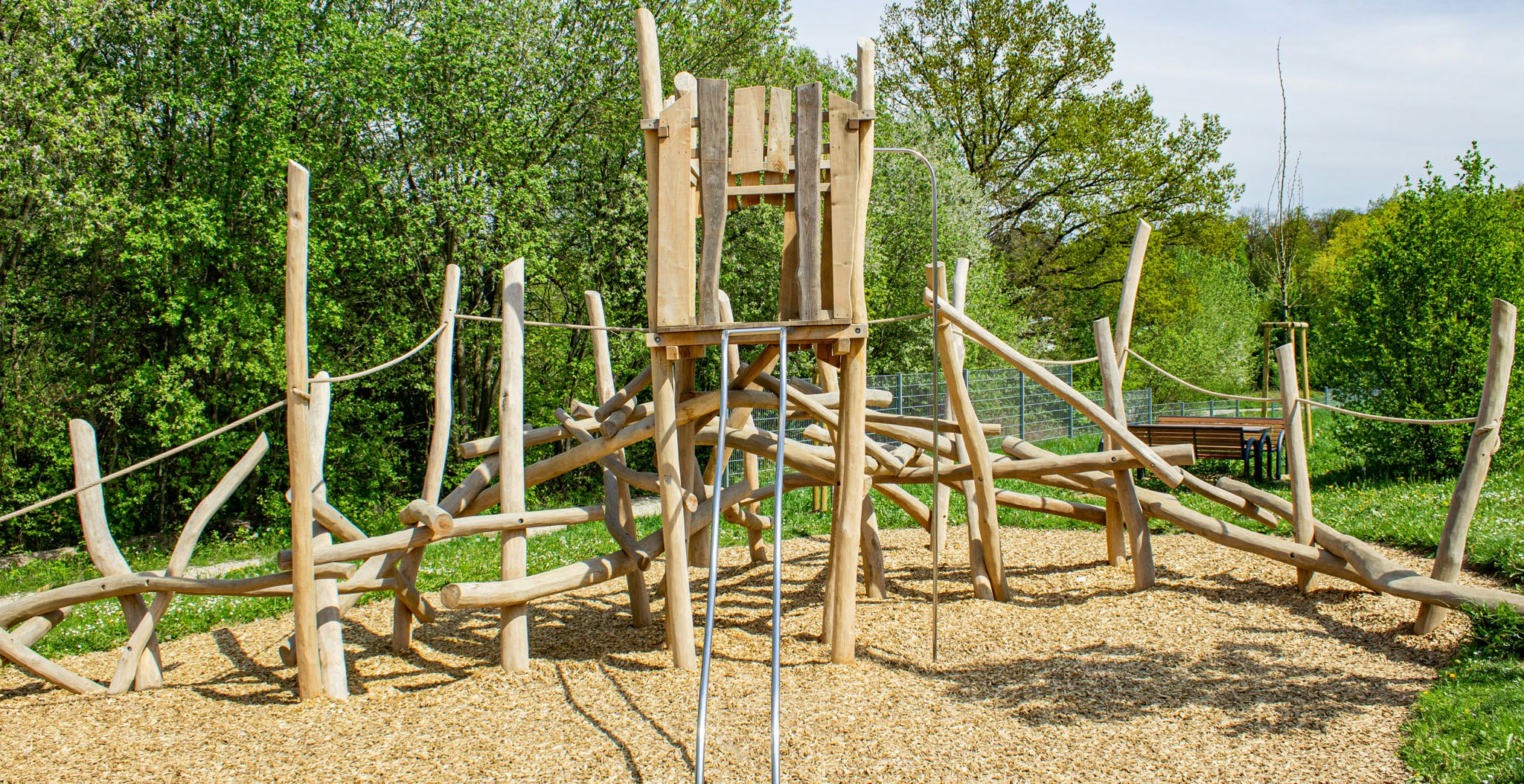 Ein Holzturm mit einer Rutsche, Kletterbalken und Seilen