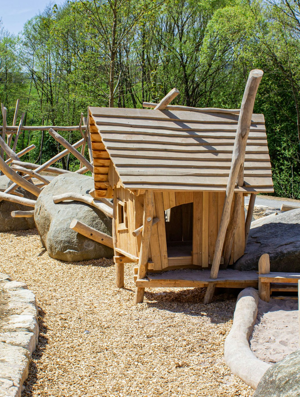 Ein Häuschen aus Holz mit Sandkasten und Steinen