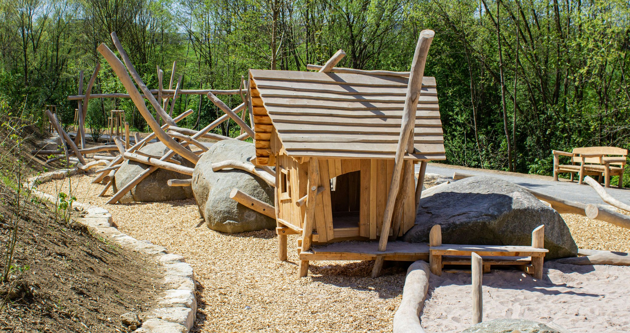 Ein Häuschen aus Holz mit Sandkasten und Steinen