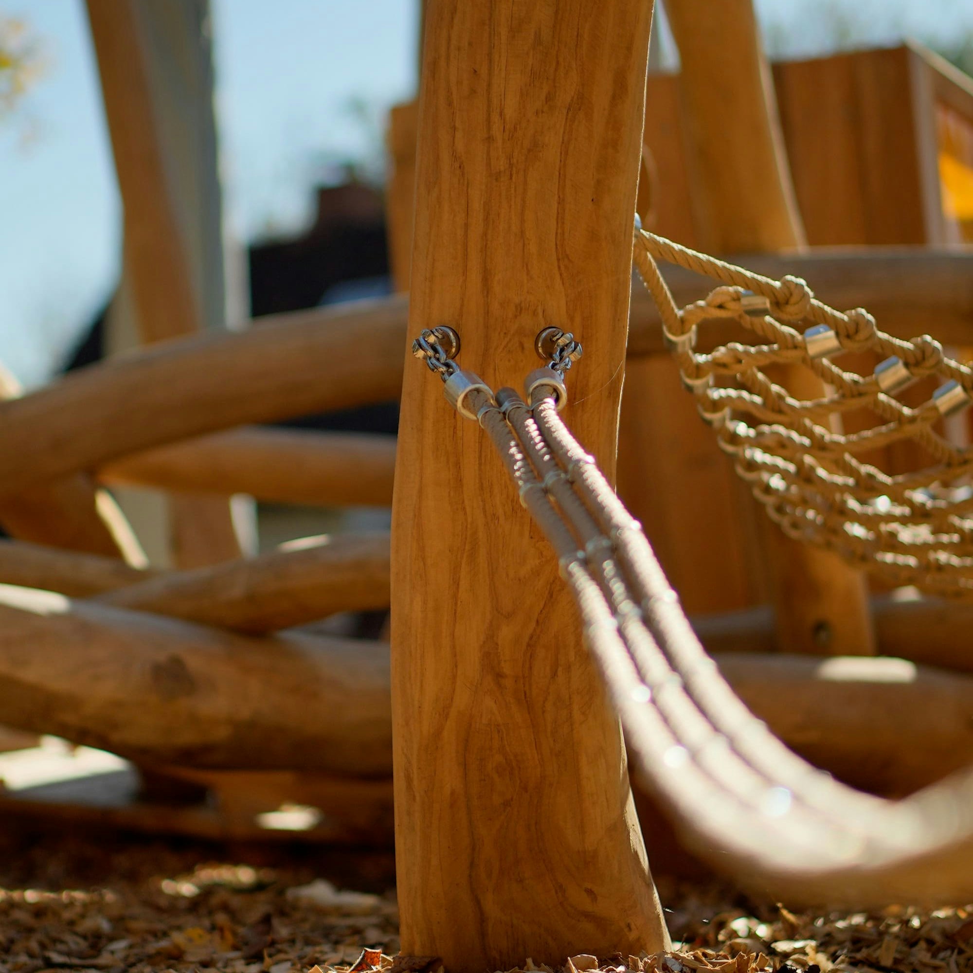 Eine hölzerne Spielplatzstruktur mit Seilen, die an einem vertikalen Holzpfosten befestigt sind.