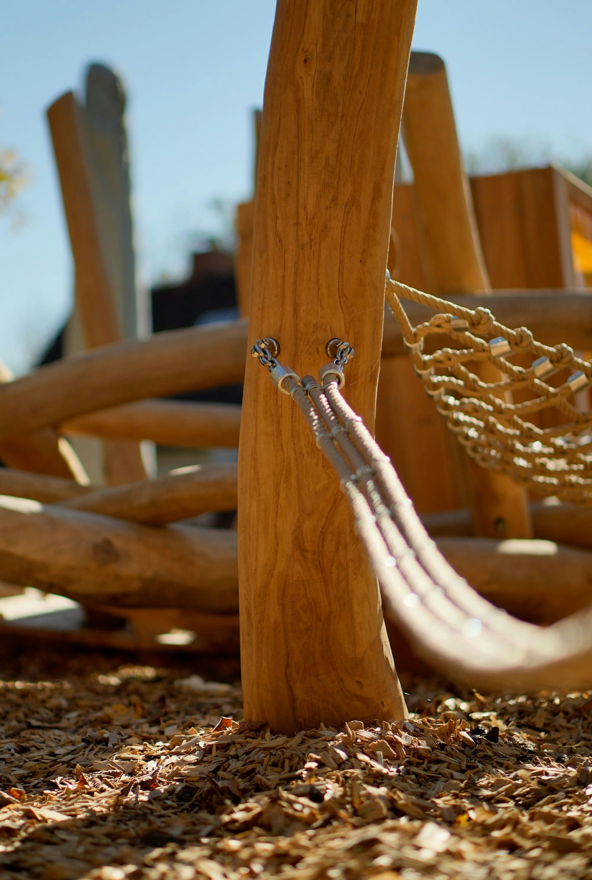 Eine hölzerne Spielplatzstruktur mit Seilen, die an einem vertikalen Holzpfosten befestigt sind.
