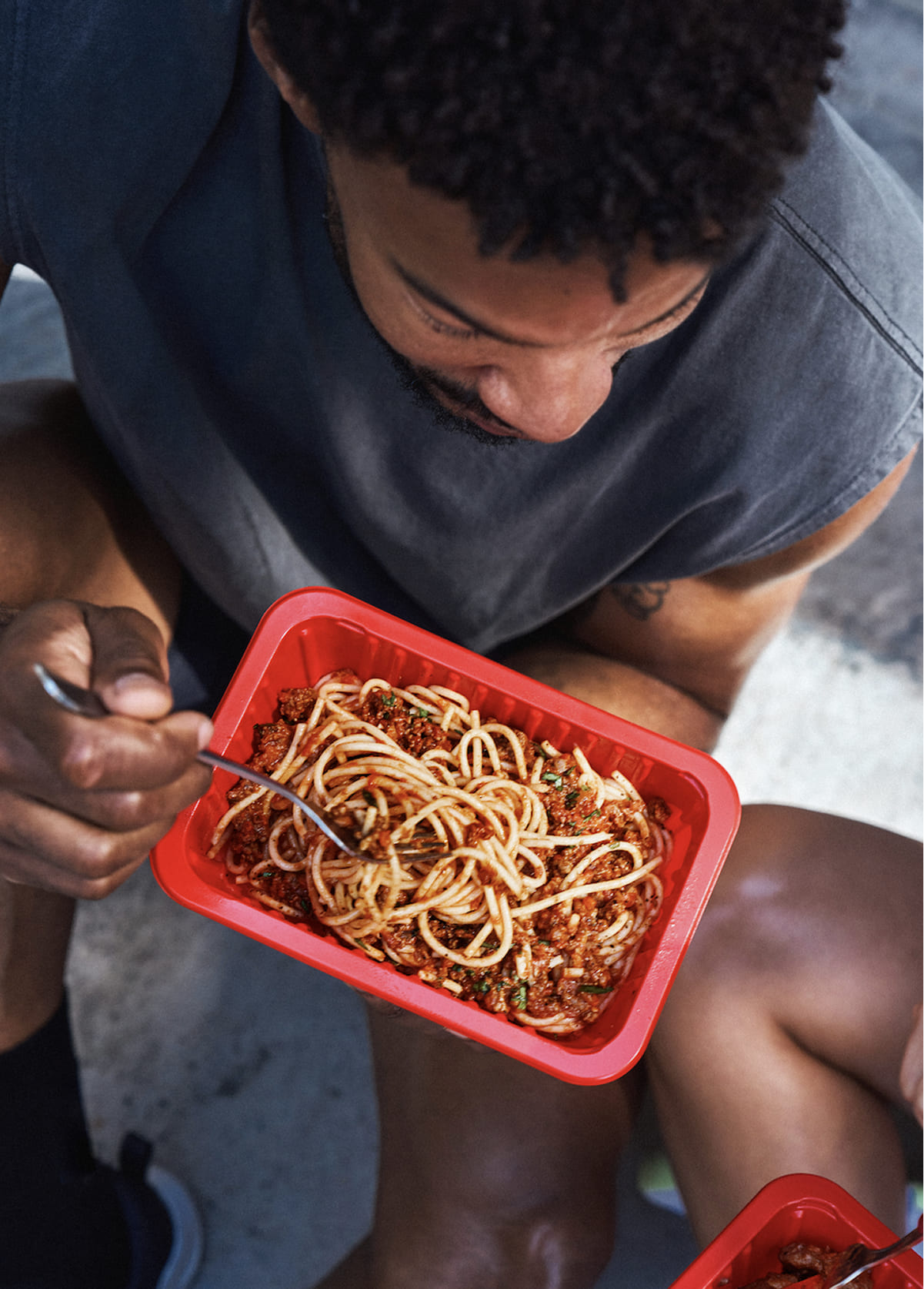 Man enjoying a healthy meal with chicken, broccoli, and sweet potatoes, alongside a My Muscle Chef meal package.