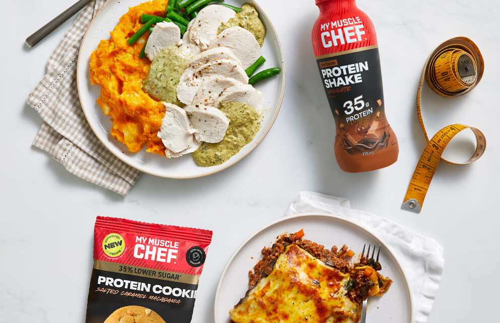 Man enjoying a healthy meal with chicken, broccoli, and sweet potatoes, alongside a My Muscle Chef meal package.