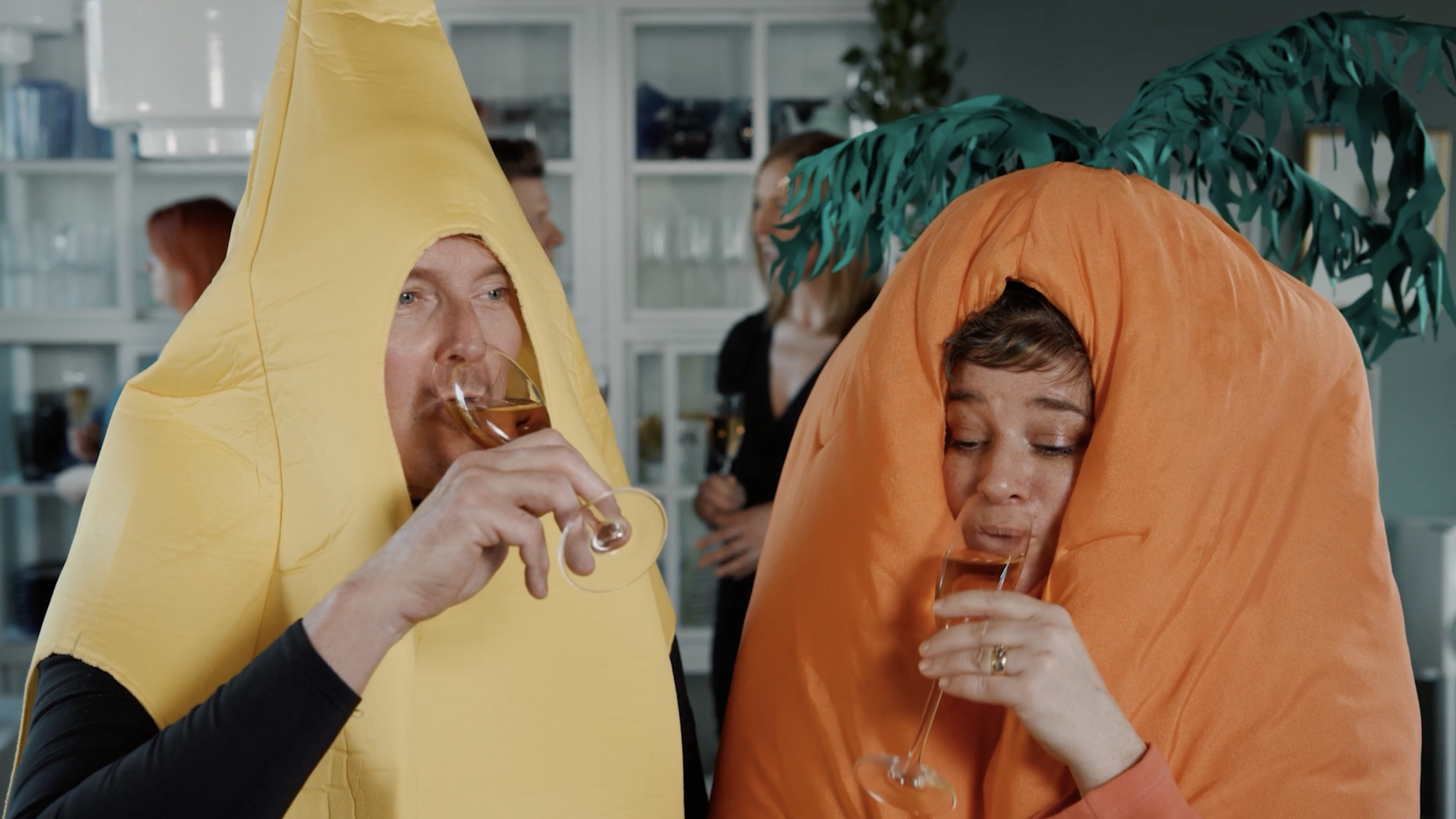 two people dressed as banana and carrot drinking sparkling wine