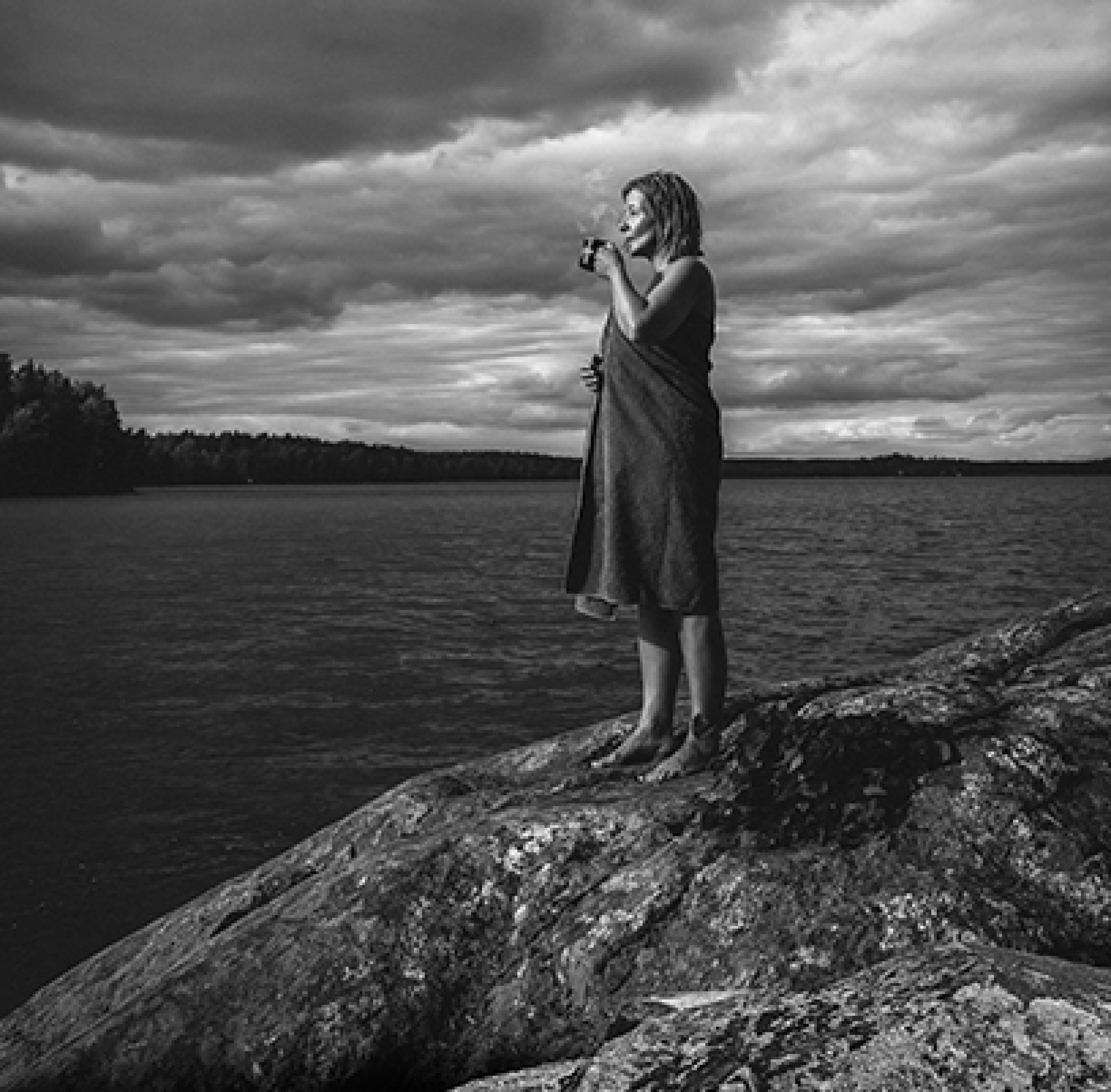 Woman drinking coffee by the seashore