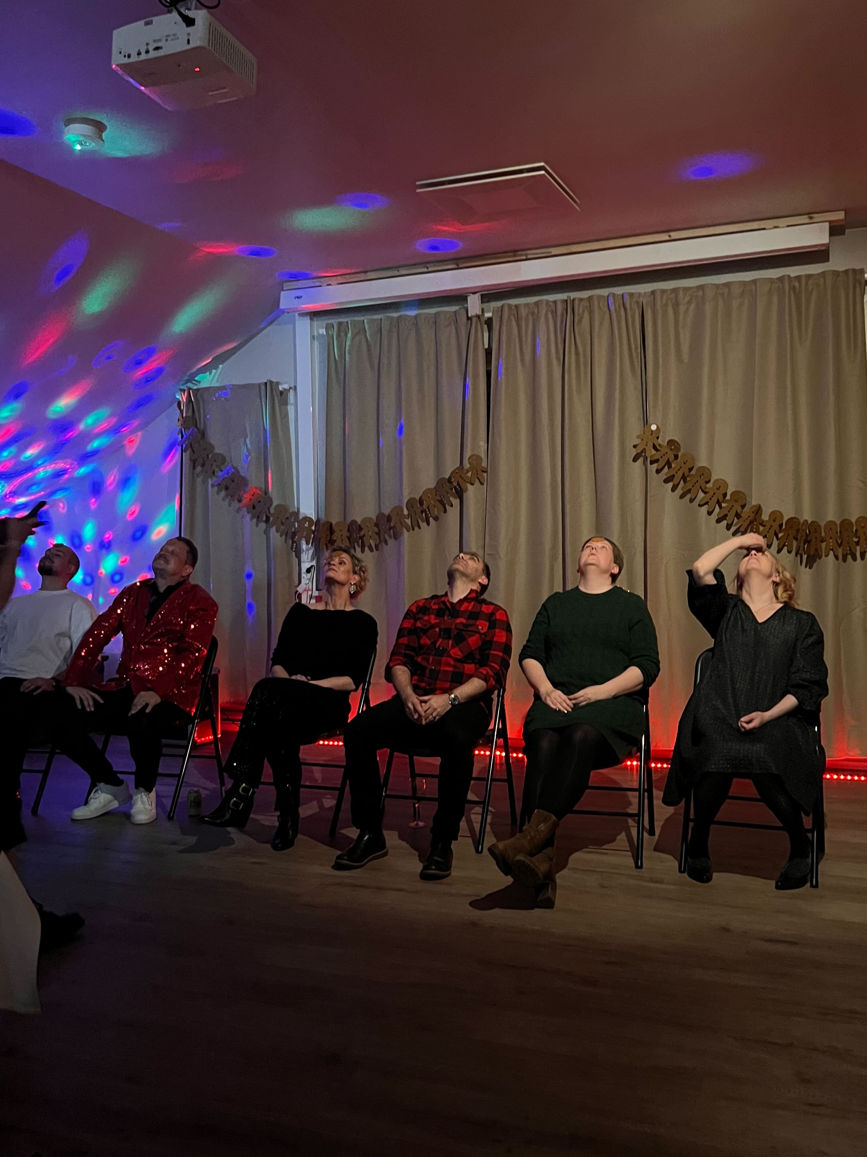 five staff members sitting in chairs, starting a playful game