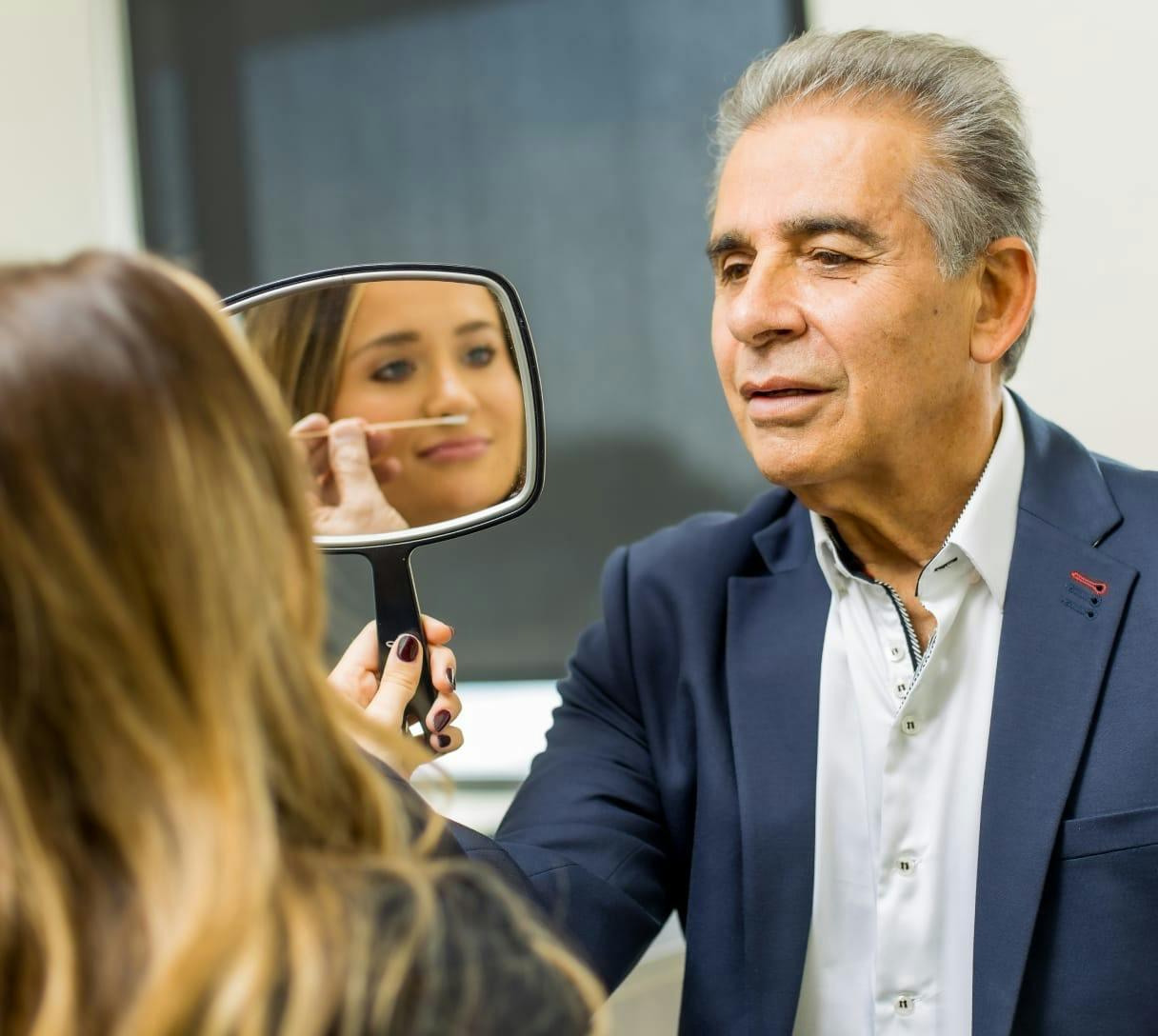 Woman looking at herself in a handheld mirror at CosmetiCare