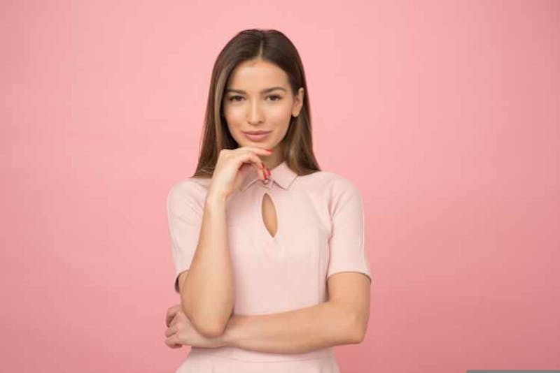 Pretty woman smiling wearing a pink shirt with a pink background.