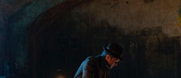 ČLOVEK SEDI ZA MIZO OB SOJU SVEČ