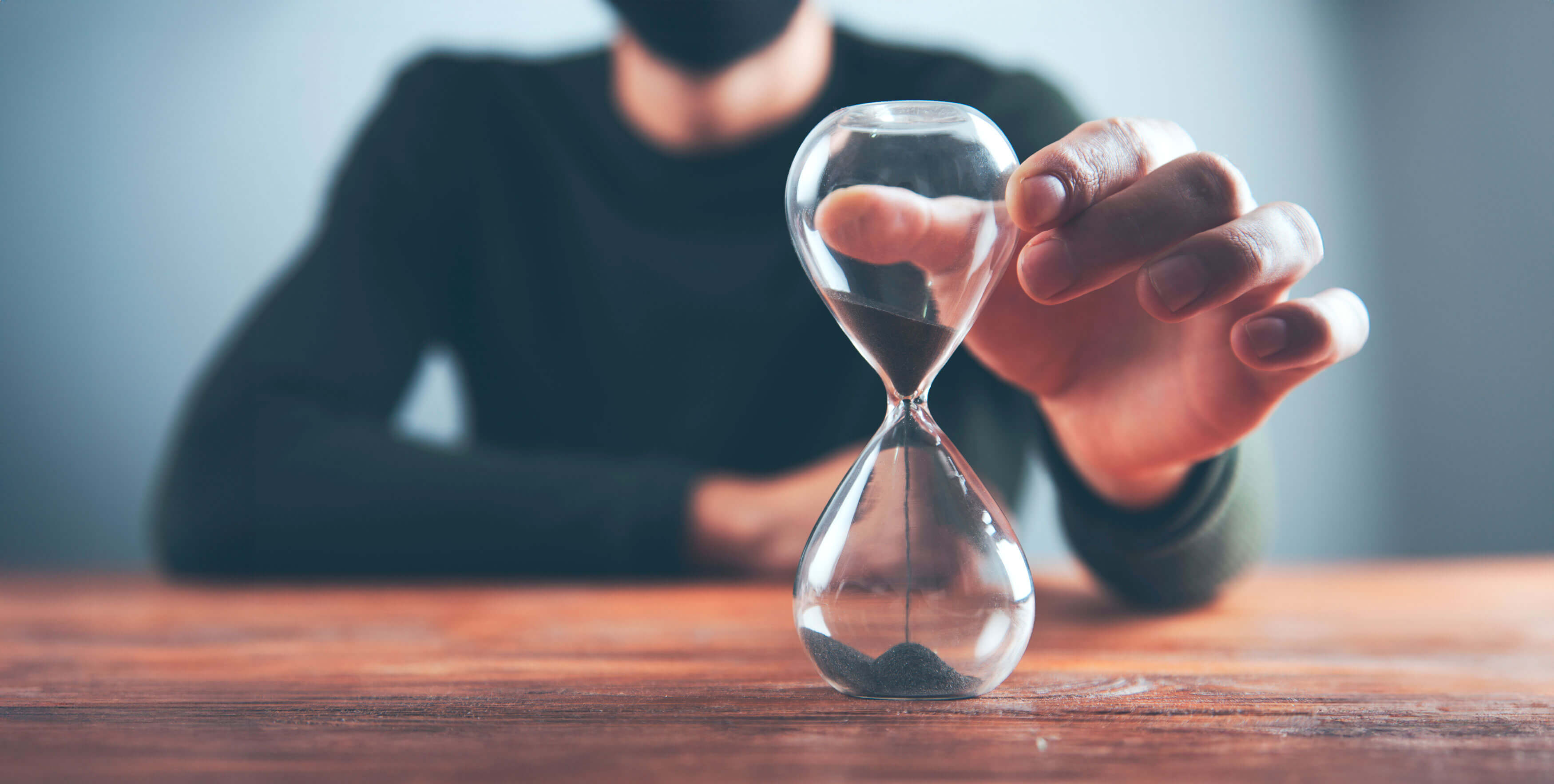 man holding timeglass on table