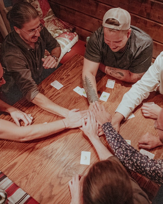 Several people from Weahead are sitting around the table with their hands on meeting in the middle