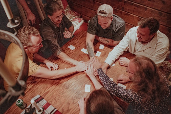 Several people from Weahead are sitting around the table with their hands on meeting in the middle