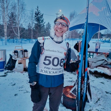 Den anställda filip som står glad med ett par skidor och is i skägget