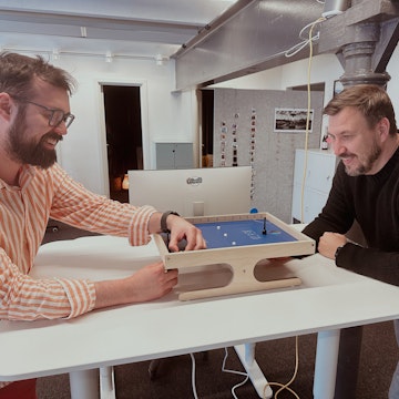 Christopher och André spelar klask tillsammans vid ett upphöjt skrivbord