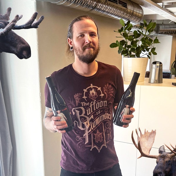 Christian som håller i två vinflaskor, omringad av älgar