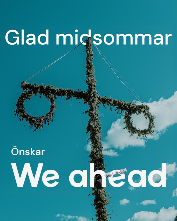Midsommarstång med texten "Glad sommar önskar We ahead", där bokstaven E har en midsommarkrans på sig.